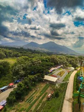 High angle view of a theme park and mountain against a dramatic cloudy sky. Stock-Fotos