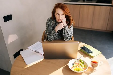 High-angle view of thinking female student working or learning online on laptop 写真素材