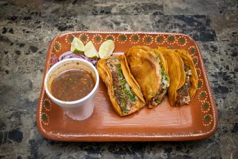 High angle view of three birria tacos next to cosome 库存照片