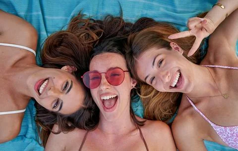 High angle view of three cheerful female women lying on the a beach towel Stock Photos