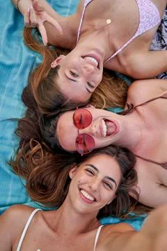 High angle view of three cheerful female women lying on the a beach towel Stock Photos