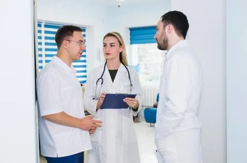 High angle view of three doctors in white coats having conversation at hospital Stock Photos