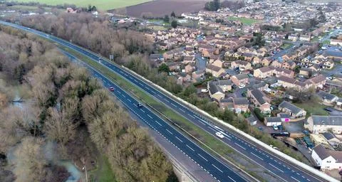 A high angle view of traffic on a dual carriageway passing next to a village Stockfoto's