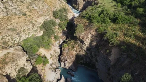 High angle view of turquoise river winding through deep rocky gorge with green t Vidéo 334324358