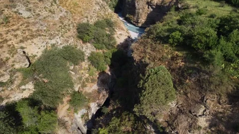 High angle view of turquoise river entering narrow deep gorge in rocky canyon Vidéo 334324405