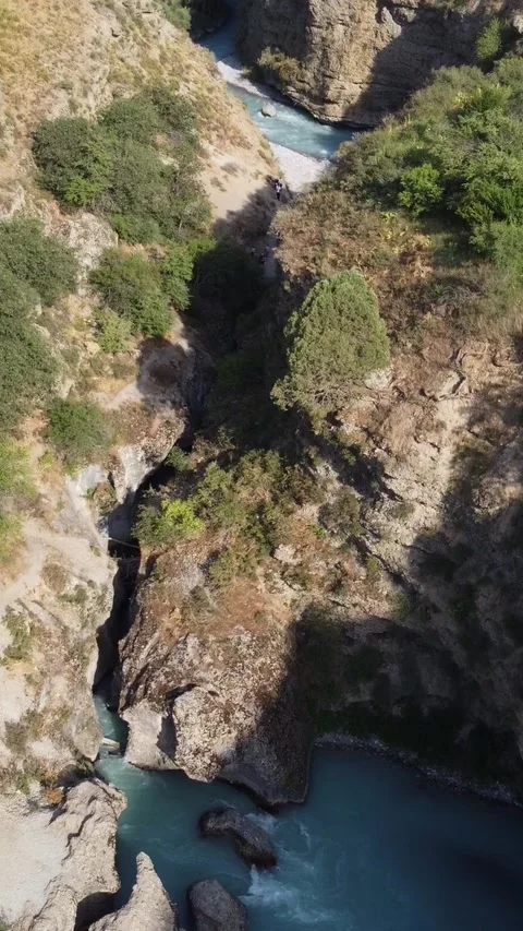  High angle view of turquoise river winding through deep rocky gorge with trees Видео 336690248