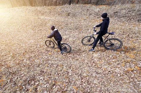 High-angle view of two individuals on bicycles traversing a leaf-covered path Fotos de archivo