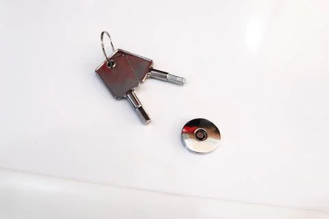 High angle view of two magnetic safety keys on a ring next to a round metal.. Stock Photos