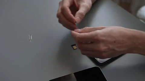 High-angle view of unrecognizable man using sim ejector tool to remove or insert Stock Footage 297631377