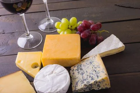 High angle view of various cheese with grapes and red wine on wooden table, copy Stock Photos