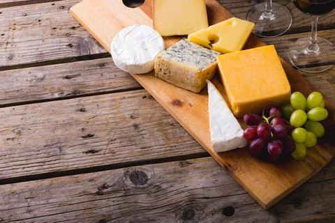 High angle view of various cheese with grapes on wooden board at table, copy Stock Photos