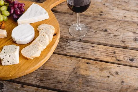 High angle view of various cheese with grapes and red wine on wooden table, copy Stock Photos