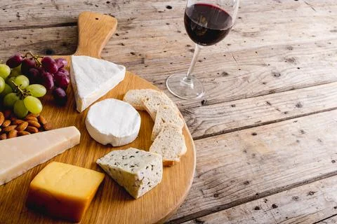 High angle view of various cheese with grapes and red wine on wooden table, copy Stock Photos