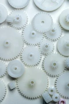 High-angle view of various small white plastic gears and cogwheels scattere.. Stock Photos