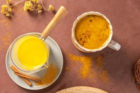 High angle view of a warm turmeric latte served in a ceramic cup and glass .. Stock Photos