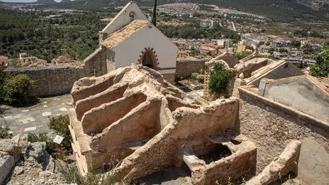 High angle view of weathered tombs, a small chapel, and a town in the backg.. Stock Photos