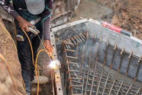 High-angle view of a welder joining steel rebar rods with bright sparks at .. Stock Photos