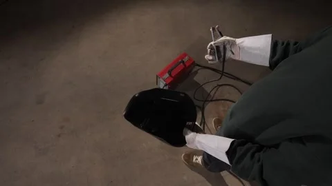 High angle view welder wearing protective gloves picking up a welding mask Stock Footage 342774565