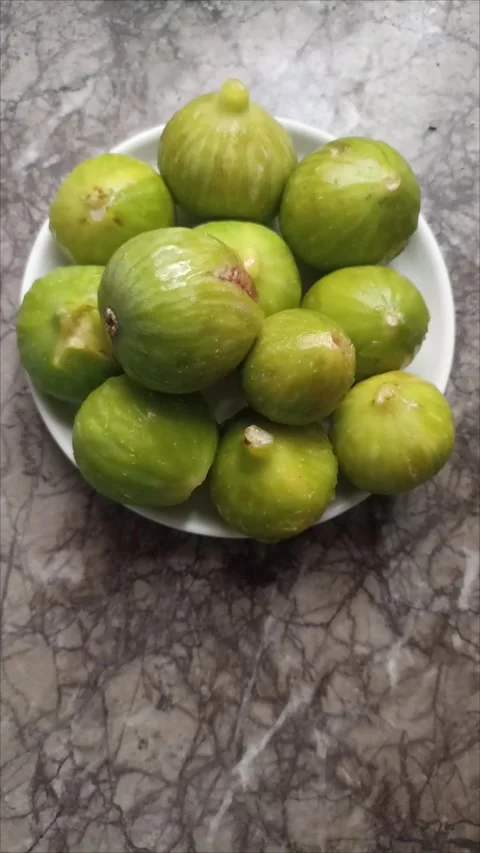 High angle view of a white ceramic plate filled with fresh ripe green figs Video stock 344740402