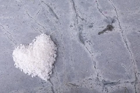 High angle view of white rock salt in heart shape pattern on table with blank Fotos de archivo