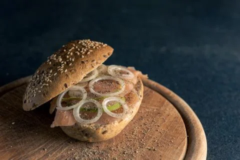 High-angle view of whole-grain bun with wild salmon, onion rings and slices o Фото