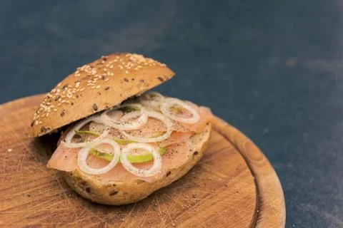 High-angle view of whole-grain bun with wild salmon, onion rings and slices o Fotos de archivo