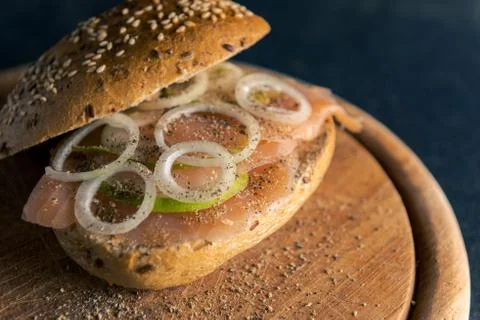 High-angle view of whole-grain bun with wild salmon, onion rings and slices o Stock-Fotos