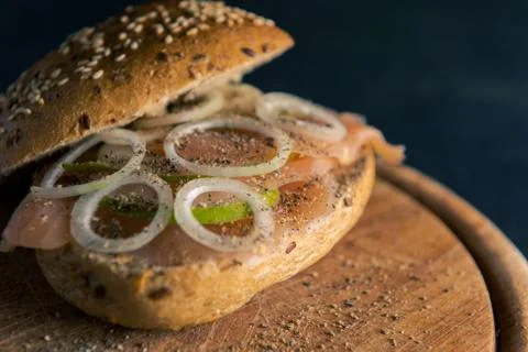 High-angle view of whole-grain bun with wild salmon, onion rings and slices o Stock Photos