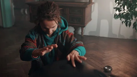 High angle view of a woman with dreadlocks that plays on a hangpan and stops. Stock Footage 180655178