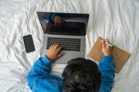 High angle view of woman using laptop and writing diary on bed Stock Photos