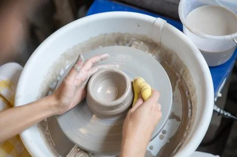 High Angle View Woman Using Sponge on Clay Bowl Rim on Wheel in pottery wor.. Stock Photos
