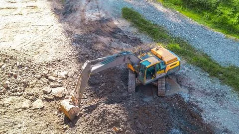 High angle view of a yellow excavator digging soil at an industrial work site Stock Photos
