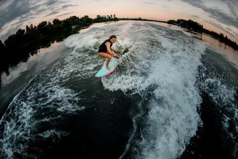 High angle view of young woman on surf style wakeboard ride on splashed river 스톡 사진