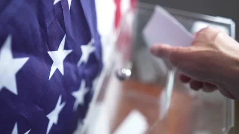 High angle of voter dropping ballot into transparent box with US flag on Stock Footage 342246205