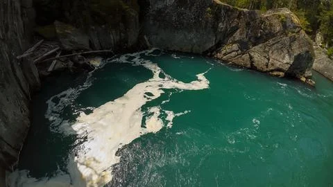 High angle wide shot looking down at swirling white water foam on a river poo Foto stock