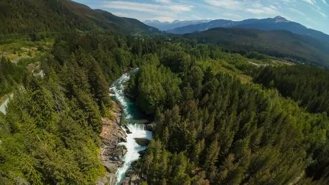 High angle wide shot overlooking a river waterfall inside a dense pine forest Stock-Fotos