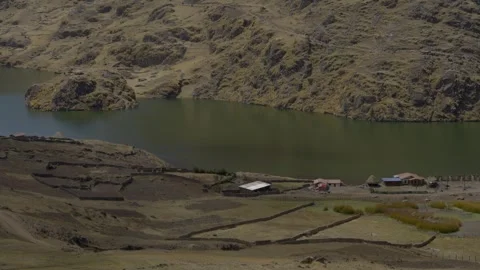 High-angle wide shot of a tranquil mountain lake and small rural settlement in Stock Footage 347036571