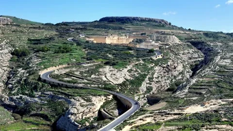 High angle wide shot of winding asphalt road snaking through sun-drenched Vídeo Stock 331109848