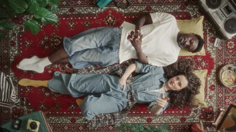 High Angle of Young Man and Woman Lying on Vintage Carpet and Talking 库存影片 339847846