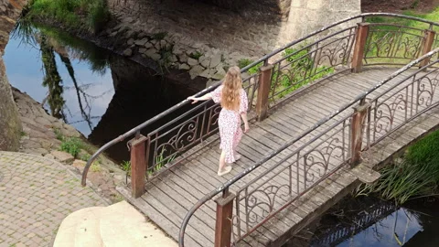 High angle of young woman walking on wooden bridge over stream Video stock 337551986