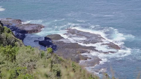 High Angle Zoom-Out: Ocean Waves Crashing on Rugged Coastal Rocks Stock Footage 317235935