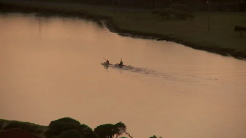 High angled extreme long shot of silhouetted people canoeing down a river Stock Footage 310385966
