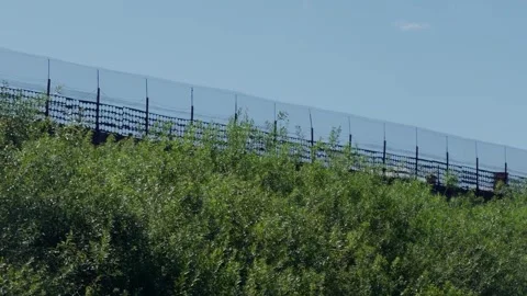 High border barrier fence border on hill slope with green trees, tracking shot Stock Footage 340892765