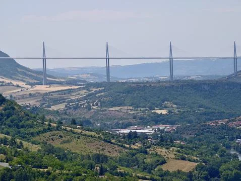 High cable stayed bridge spanning green valley with rolling hills, patchwor.. Stock Photos
