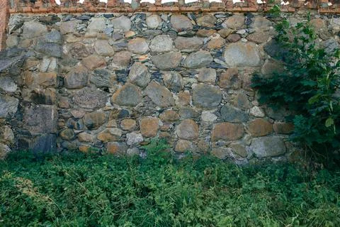 High castle wall made of large stone interspersed with small stones Stock Photos