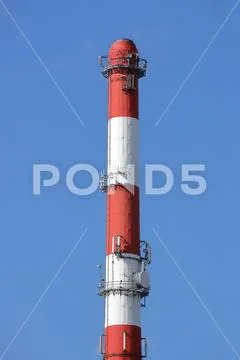 High chimney at the plant in red-white color with equipment for broadcasting Stock Photos