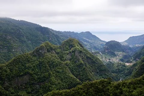 High cliffs covered with green tropical vegetation and a town in a valley a.. Stock Photos