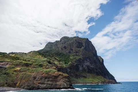 High cliffs covered with tropical vegetation in the Atlantic Ocean against .. Stock Photos