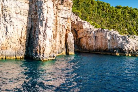High cliffs with forest and rocks on shore of Corfu island 库存照片