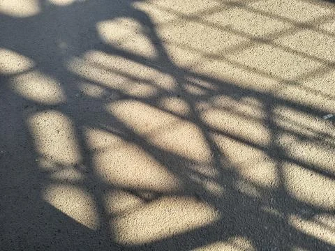 High contrast geometric grid shadow cast on textured concrete ground. Foto stock
